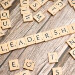 Wooden letter tiles spelling 'LEADERSHIP' on a wooden surface, symbolizing leadership qualities and skills.