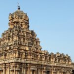 Stunning close-up of an intricately carved Hindu temple facade under clear skies, showcasing ancient architecture.